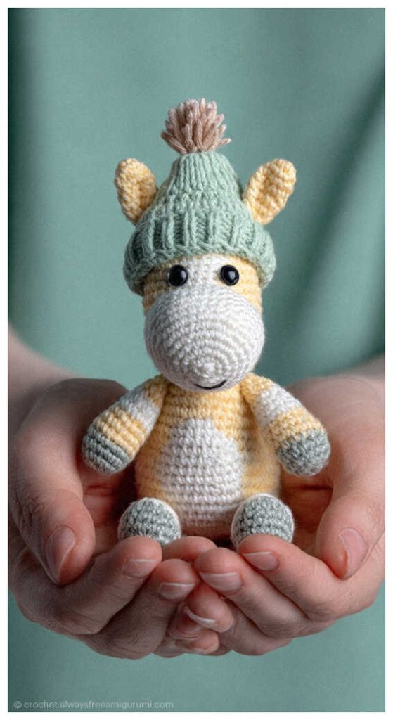 Crochet horse amigurumi doll wearing a green hat, held in hands as a handmade baby shower gift idea